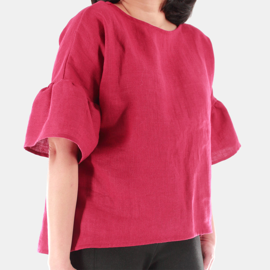 Front close up of a female model wearing womens willow bell sleeve top in Midweight Linen. High-low hem finishing from front to back. Color of the top is Burgundy.