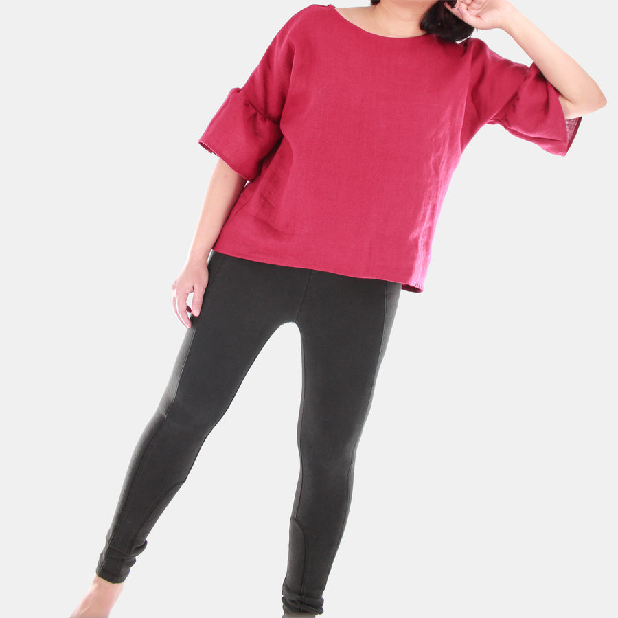 Full body view of a female model wearing womens willow bell sleeve top in Midweight Linen. High-low hem finishing from front to back. Color of the top is Burgundy.