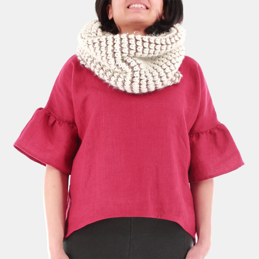Front close-up of a female model wearing womens willow bell sleeve top in Midweight Linen. Accessorized with white/ivory infinity scarf. High-low hem finishing from front to back. Color of the top is Burgundy.