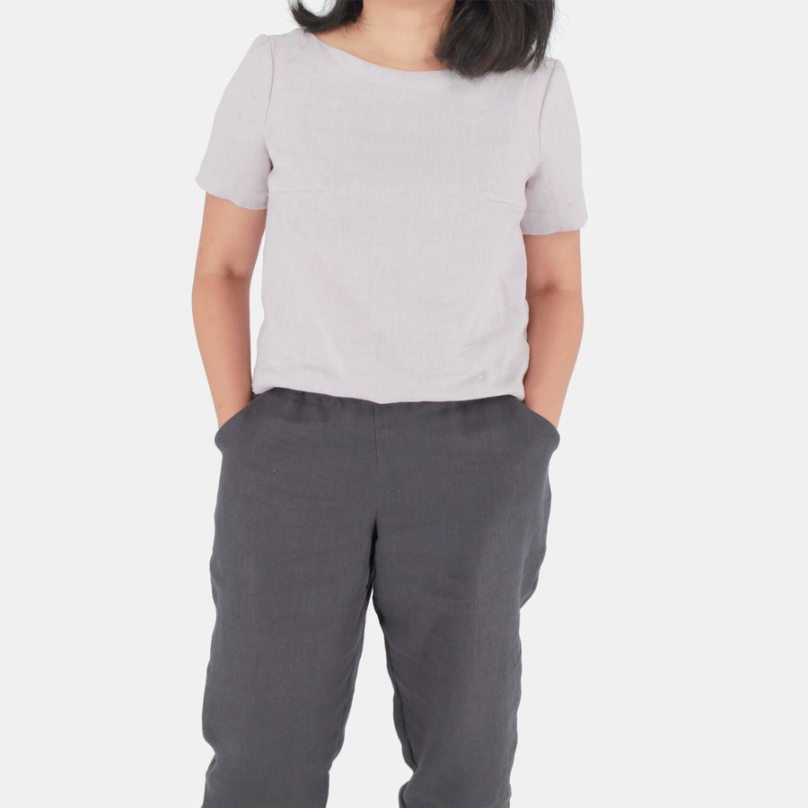 A female model wearing womens crop top in Midweight Linen. Color of the top is snow grey.