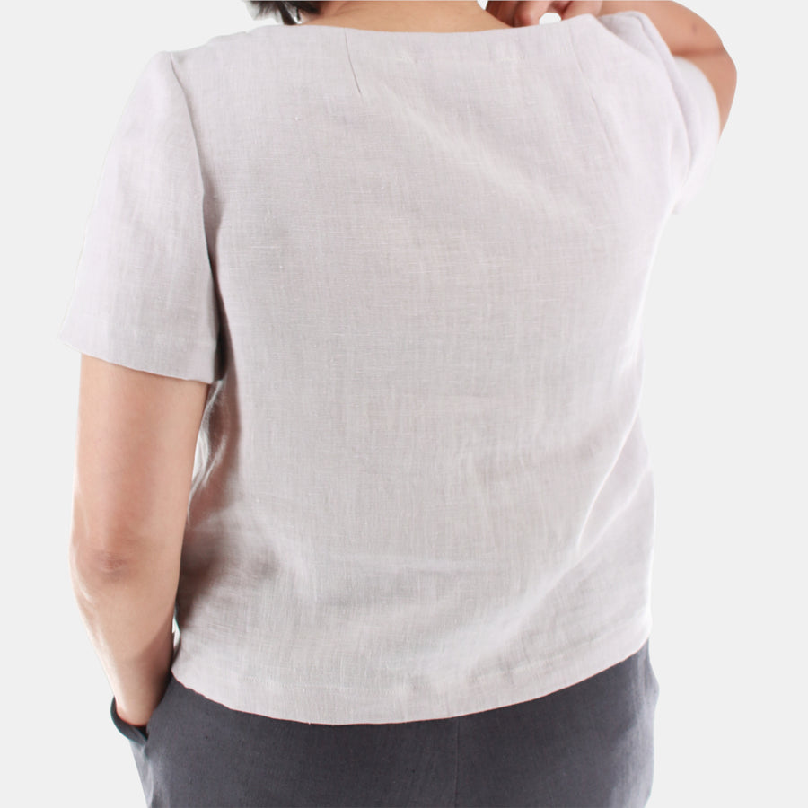 Back view of a female model wearing womens crop top in Midweight Linen. Color of the top is snow grey.